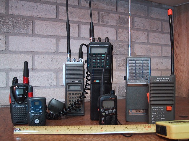 Several handheld walkie-talkies of different makes standing side by side, for storm prep in Pensacola, FL