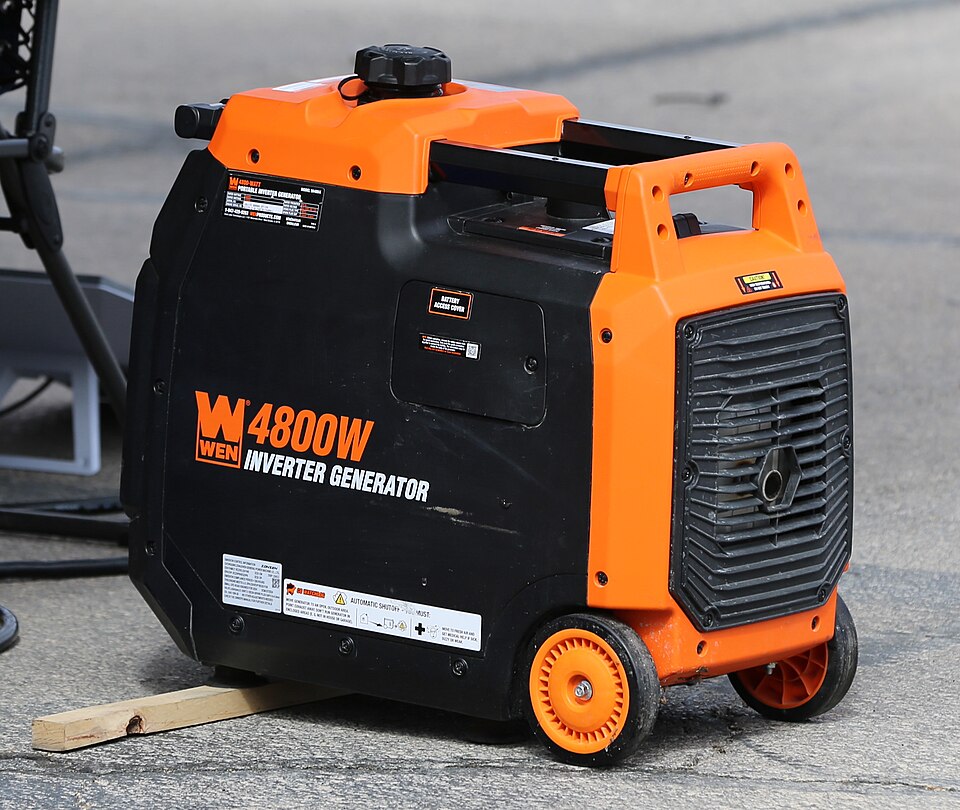 An orange and black WEN 4800 inverter generator with wheels, sitting on pavement, for storm prep in Pensacola, FL